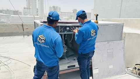Two technicians servicing an open rooftop air-conditioning unit.